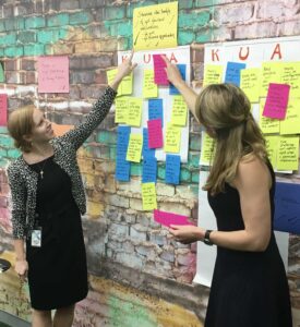 Katie Bowman and Sara Farley pointing at sticky notes guiding the discussion around knowns, unknowns, and assumptions
